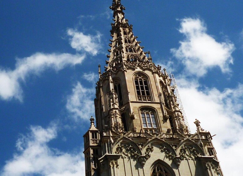 A tall, ornate church tower with intricate architectural details against a blue sky with clouds. 3