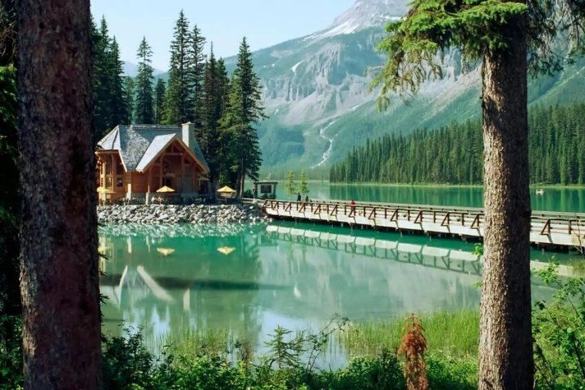 A lodge by a lake with a wooden deck and a mountain backdrop. 4