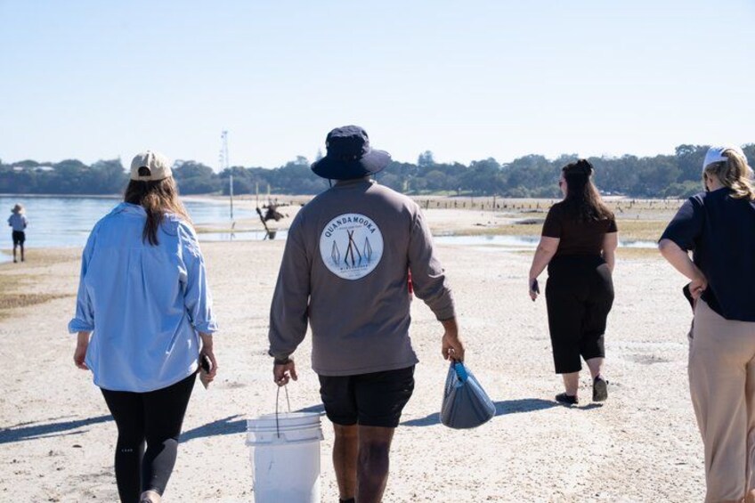 People walking on a sandy beach with a body of water in the background. 4