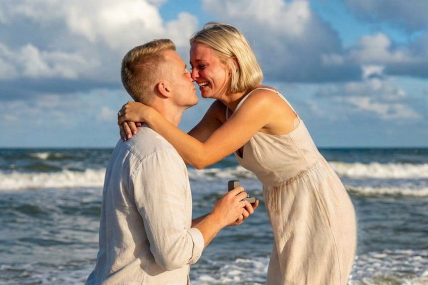 A couple embracing on a beach with ocean waves in the background. 4