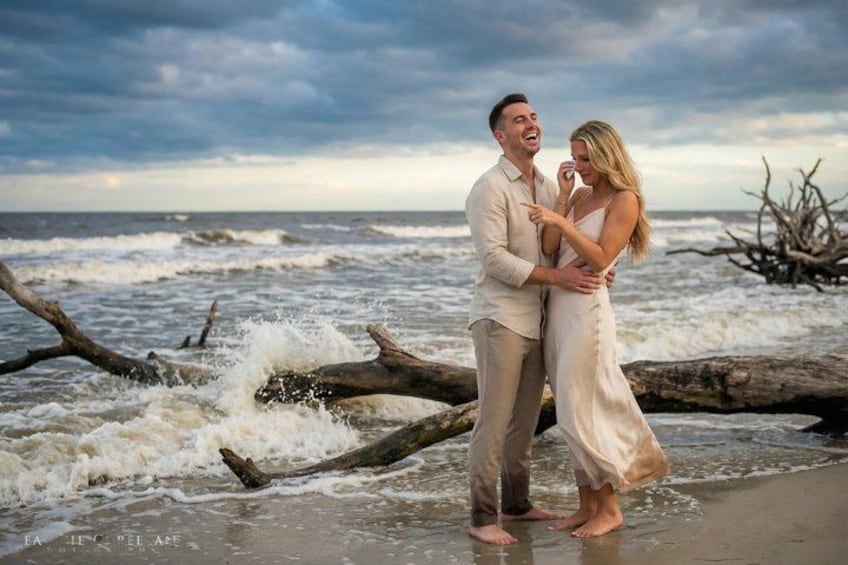 A couple standing on a beach with waves crashing nearby. 2