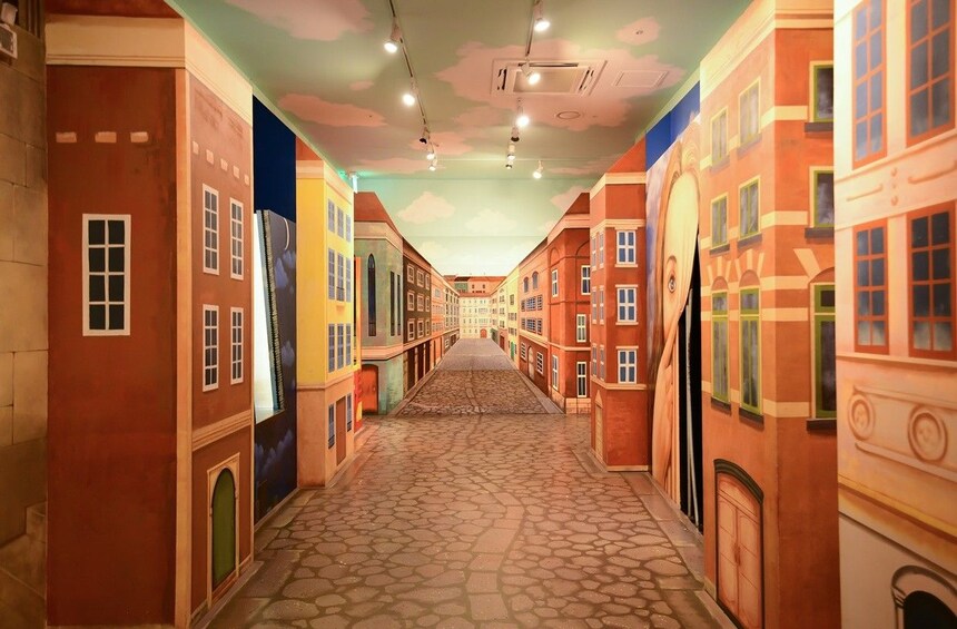 A narrow street with buildings on both sides, a cobblestone path, and a clear sky. 4