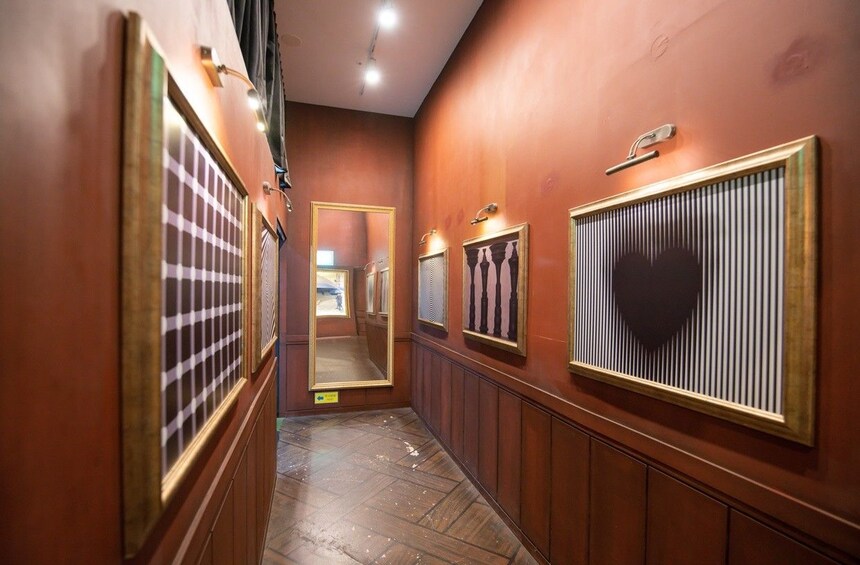 A hallway with wooden paneling, framed mirrors, and a patterned floor. 5