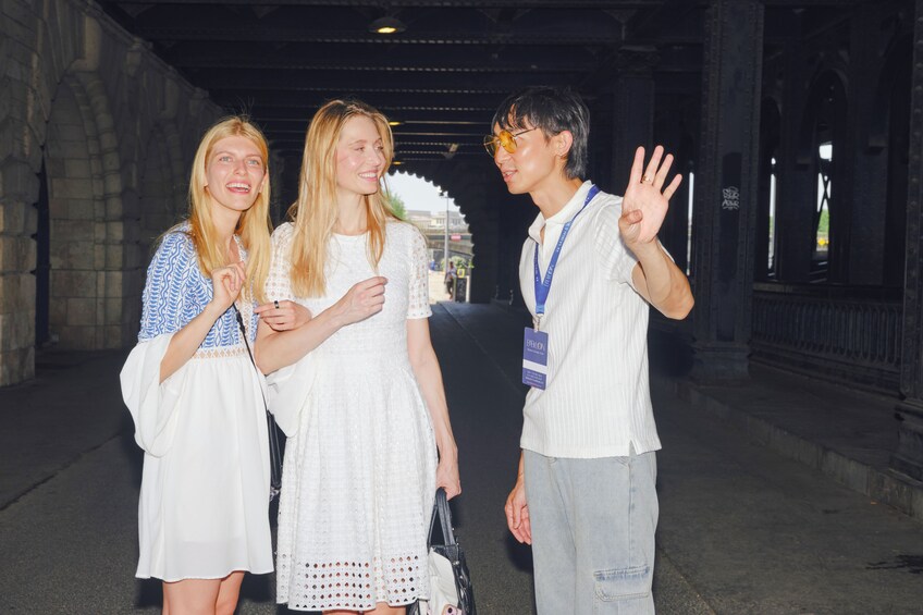 Three people walking in a tunnel with stone walls and a metal ceiling. 3