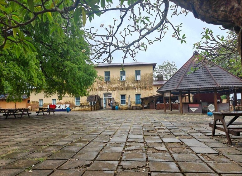 Un cortile con pavimentazione in pietra, un edificio dalla facciata invecchiata e un gazebo. 2