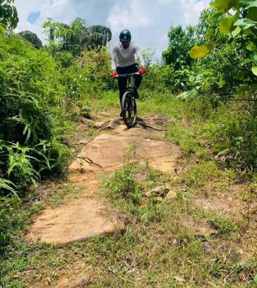 Una persona pedaleando una bicicleta por un sendero de tierra rodeado de vegetación. 2