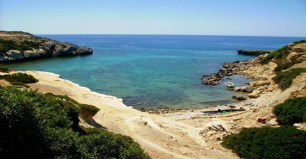 Un paisaje costero con playa de arena, afloramientos rocosos y mar azul y transparente. 3