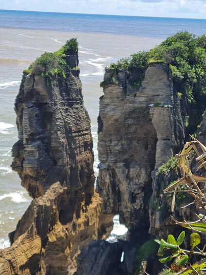 Formación rocosa en un acantilado con vegetación en la cima y vista al océano. 3