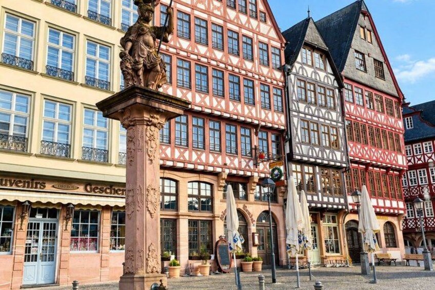 A traditional half-timbered building with a statue in front. 2