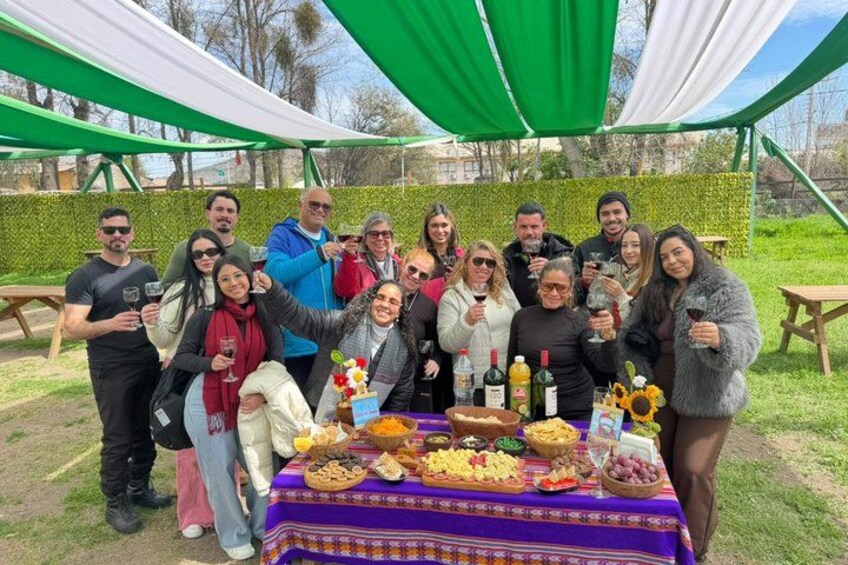 A group of people gathered around a table with food and drinks, under a green tent. 2