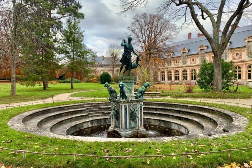 A statue of a man on a pedestal with a fountain in a park. 3