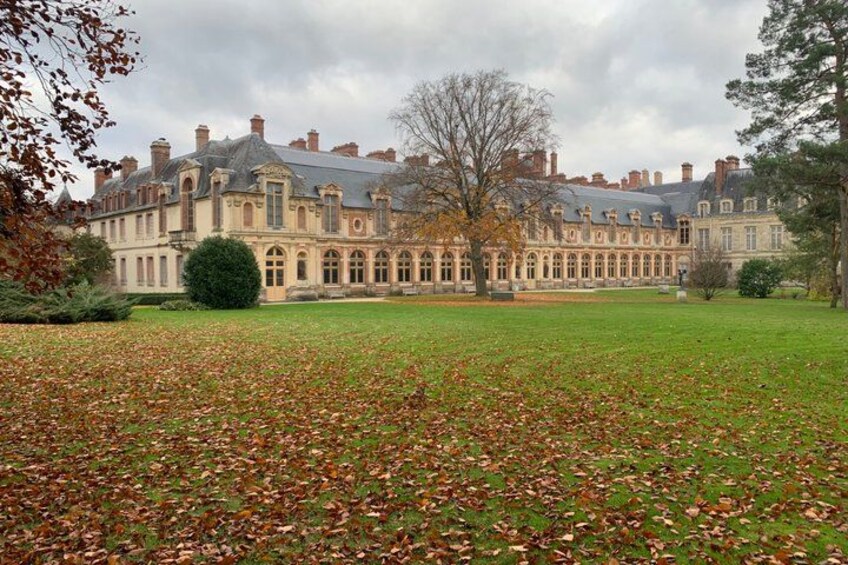 A large stately building with a symmetrical facade, surrounded by a well-maintained lawn and a few trees. 2