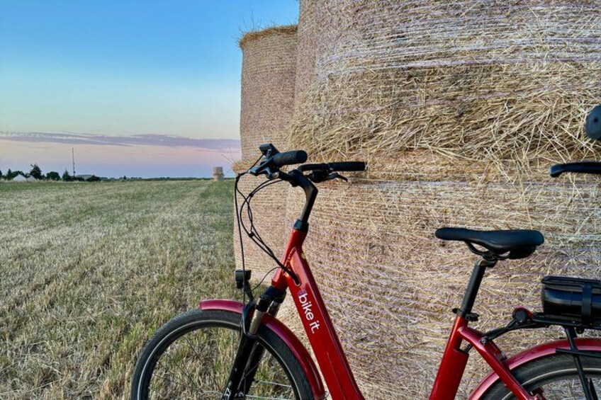 A red bicycle parked next to a hay bale in a field. 4