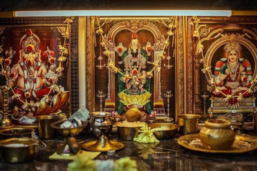 A temple interior with statues, lamps, and ritual items. 2