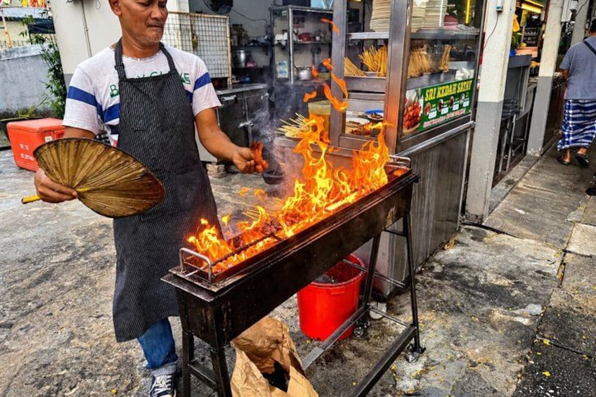 A street food vendor grilling food on a portable stove. 1