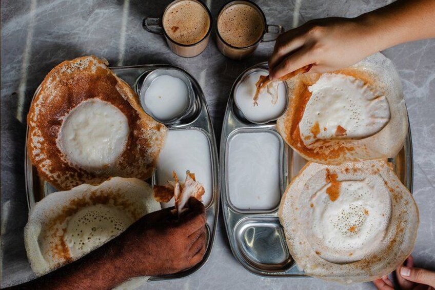 A tray with two types of food, one with a red sauce and the other with a white sauce, and two cups of a brown beverage. 3