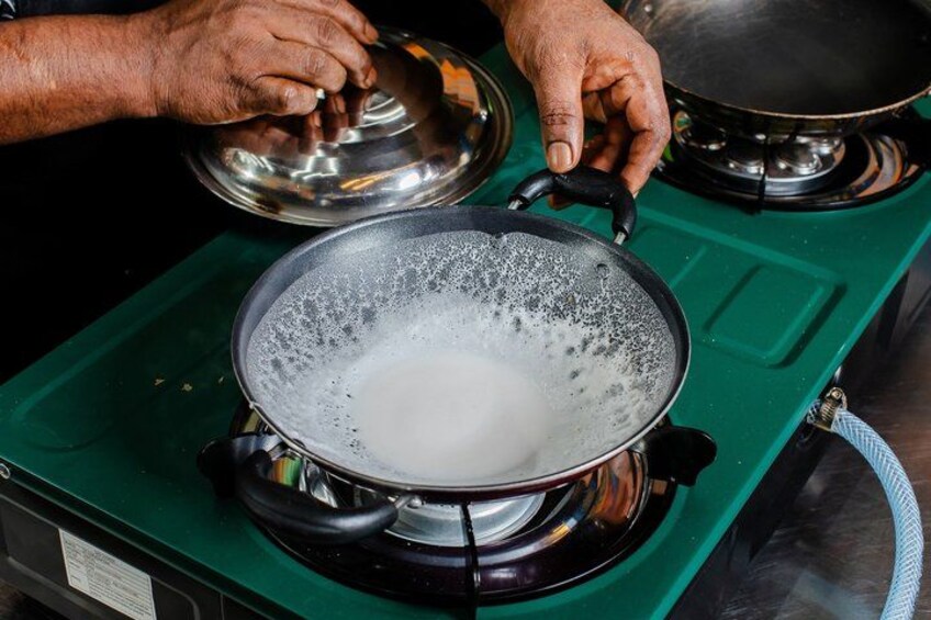 A person cooking on a stove with a pot on a green burner. 4