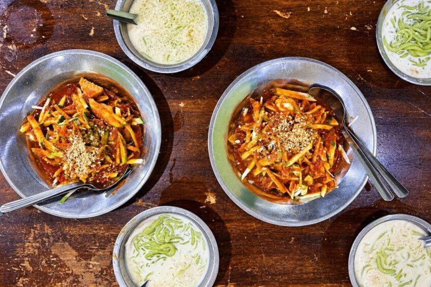A table with bowls of food, including a red dish with vegetables and a white creamy dish. 4