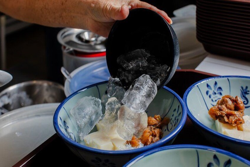 A person pouring charcoal into a bowl with ice and food. 4