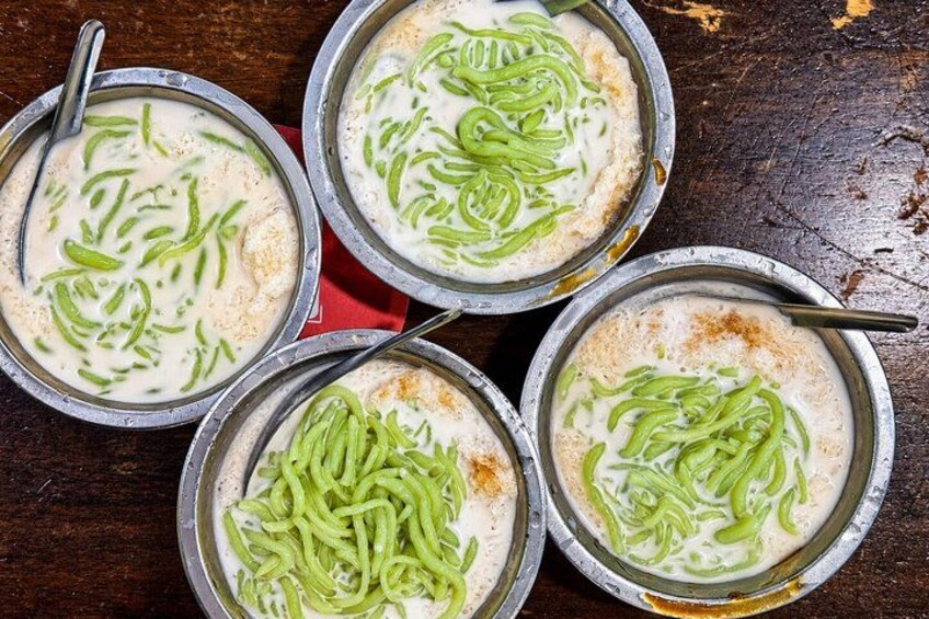 Four bowls of a creamy dish with green garnish on a wooden table. 2