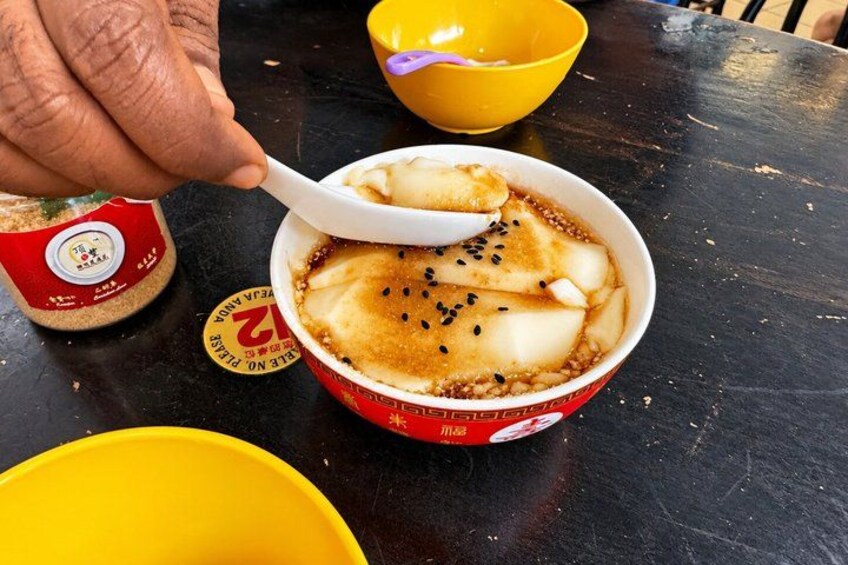 A bowl of food with a spoon, a yellow bowl, and a red container on a table. 3