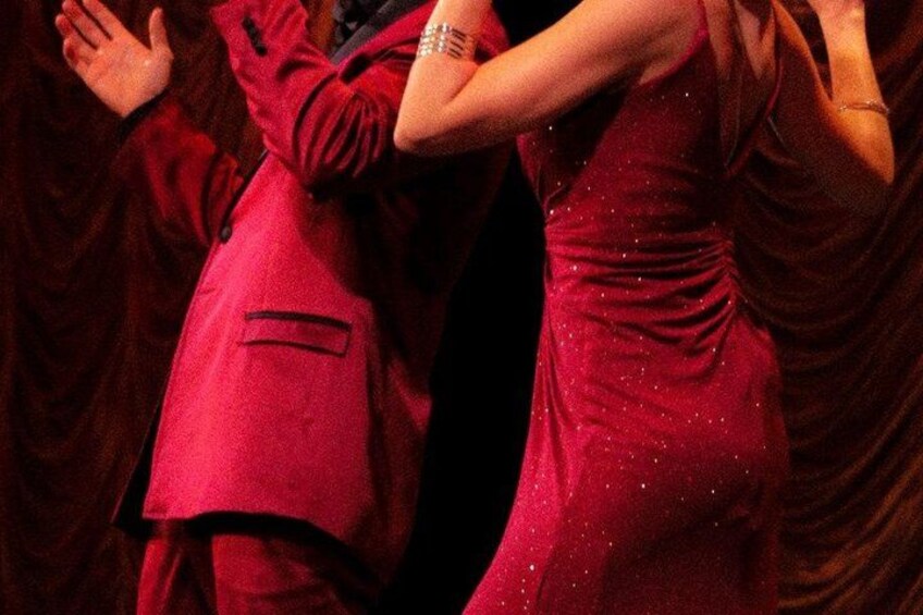 A person in a red suit dancing with another person in a red dress. 2