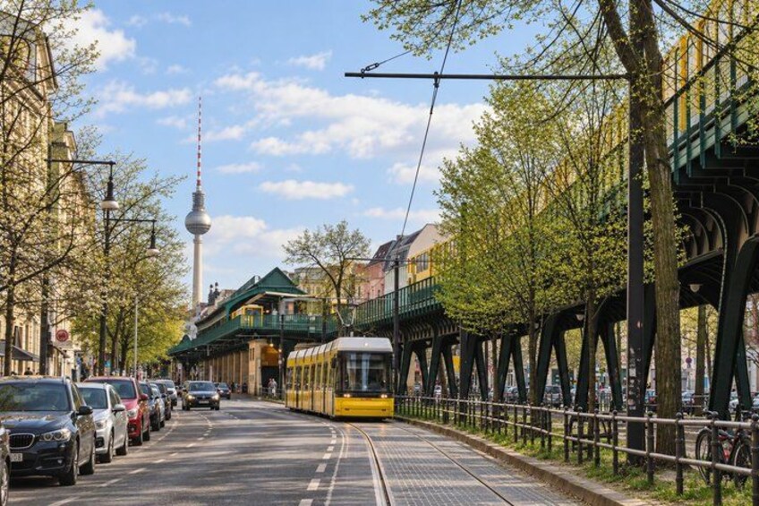 A tram on tracks, a tower in the background, and a tree-lined street. 4