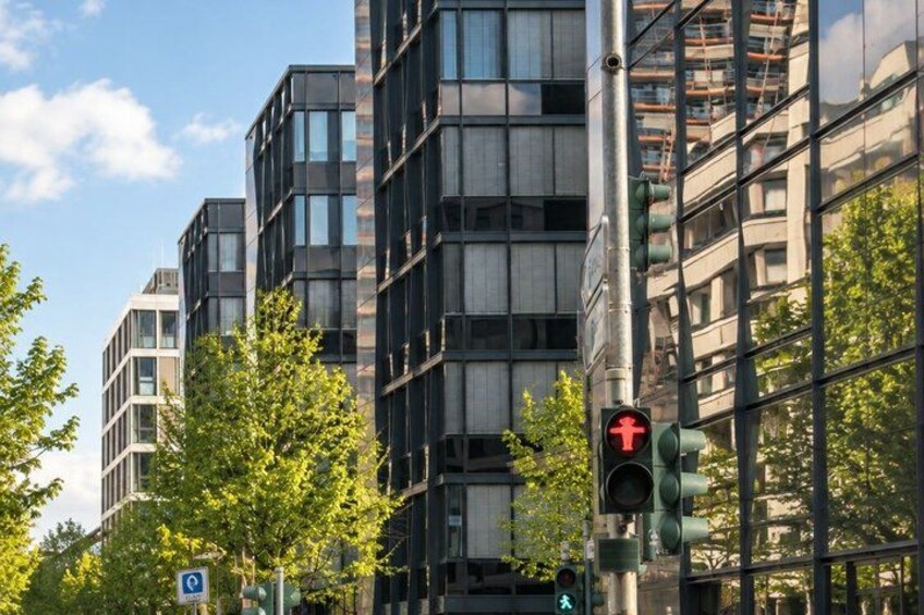 A modern building with glass windows, a traffic light, and a pedestrian crossing sign. 2