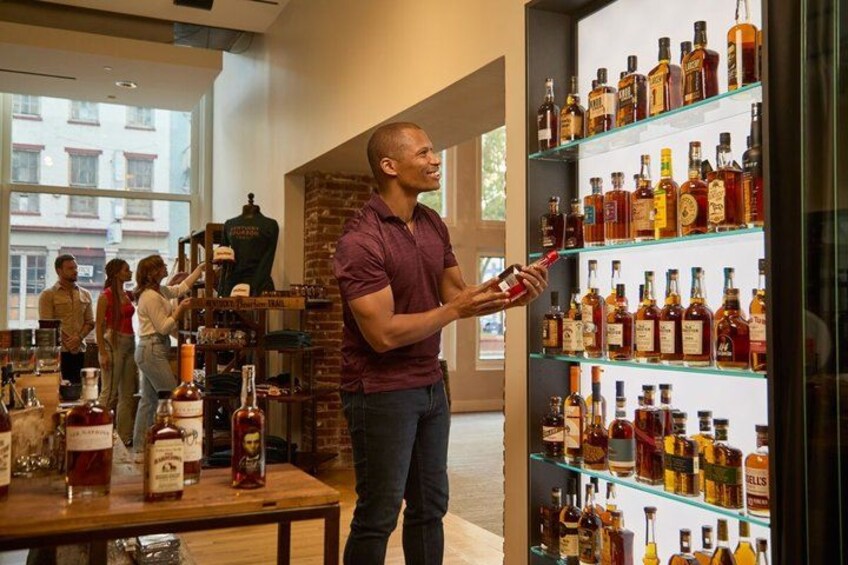 A man in a store examining bottles on shelves. 3