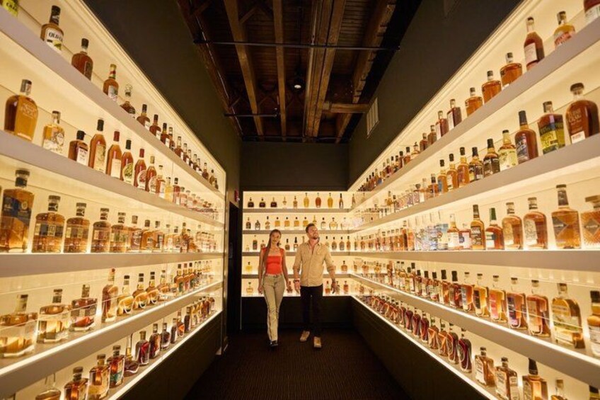 A corridor with shelves of various liquor bottles. 5