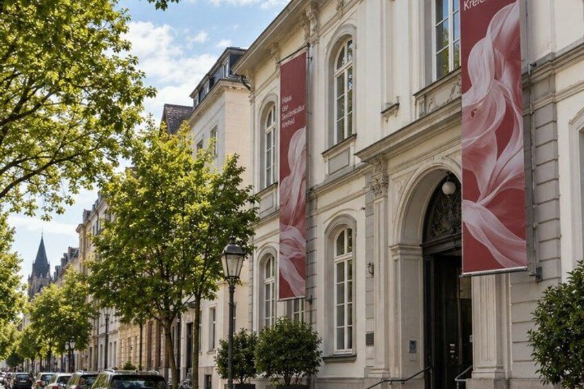 A street with classical architecture, banners, and parked cars. 4
