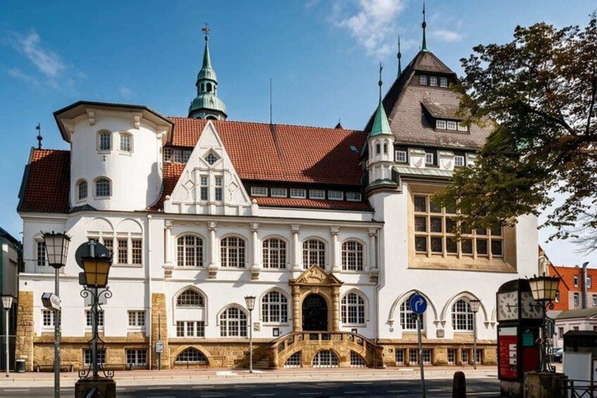 A historic building with a red-tiled roof, a prominent tower, and a large arched entrance. 5