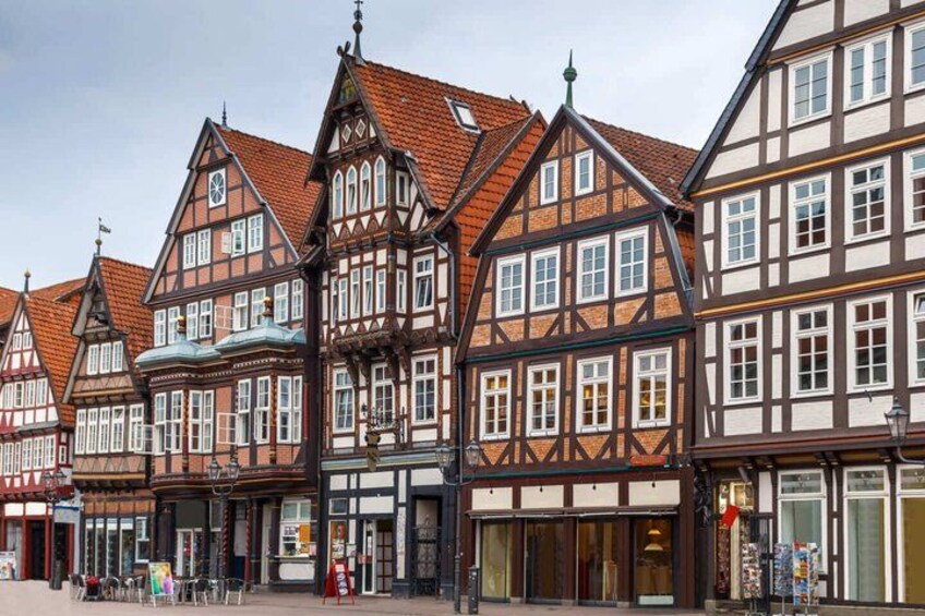 A row of traditional half-timbered buildings with red-tiled roofs and white facades. 3