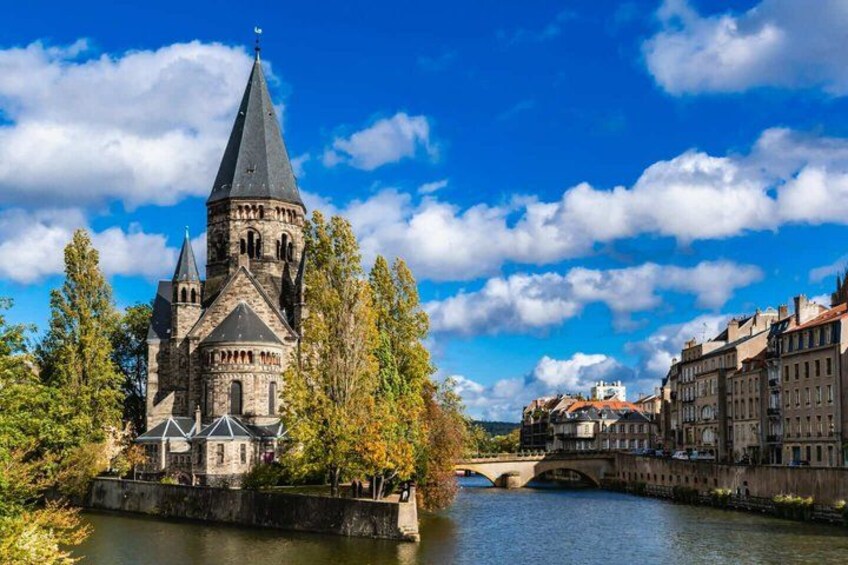 A historic church with a tall spire, a river, and a bridge. 1