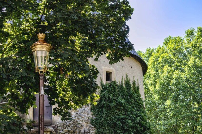A white building with a rounded roof, a street lamp, and lush green trees. 3