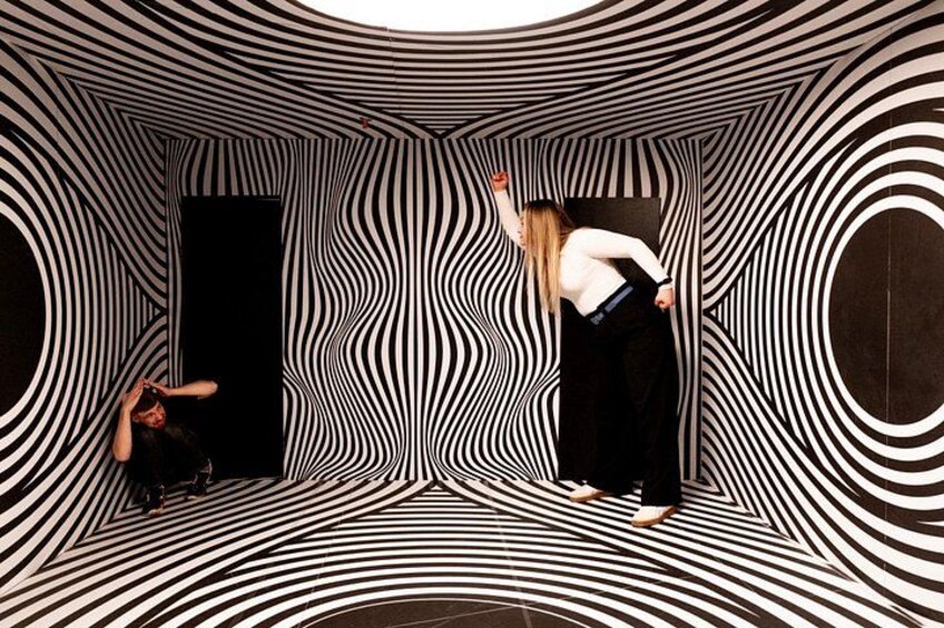 A person in a room with a black and white striped pattern, standing and bending over. 4