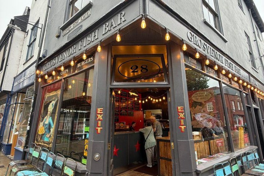 A fish bar with a number 28 sign, a person inside, and a menu board outside. 4