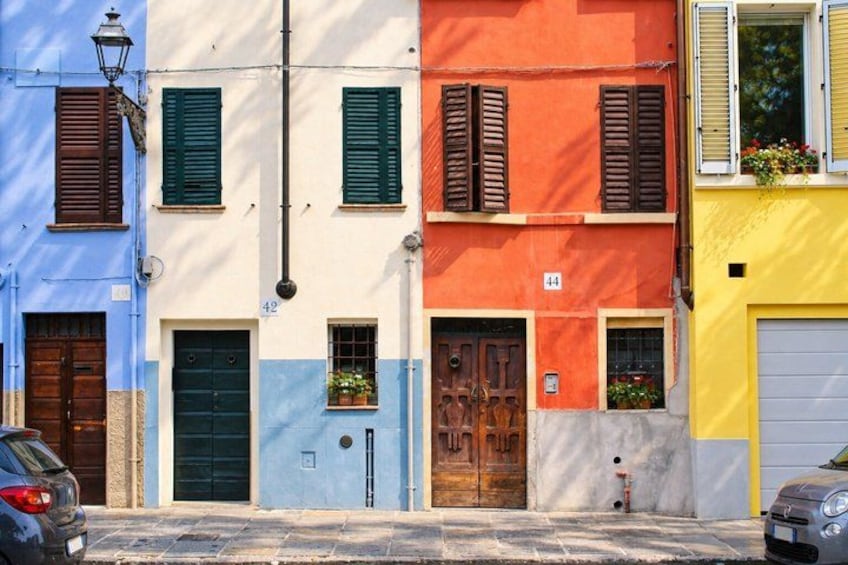 A row of colorful buildings with distinct architectural styles, including doors and windows with shutters. 2