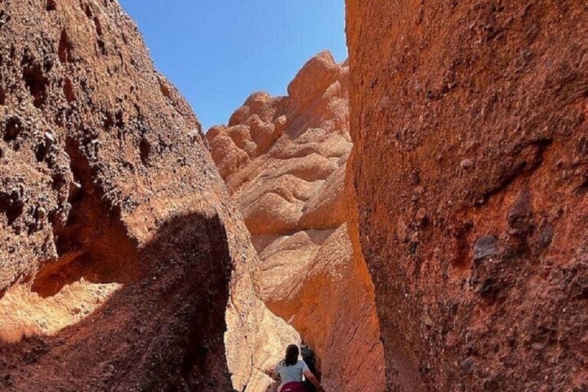 A canyon with red rock formations and a person hiking. 5