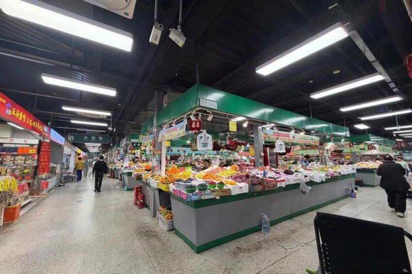 A supermarket interior with produce stands and shoppers. 3