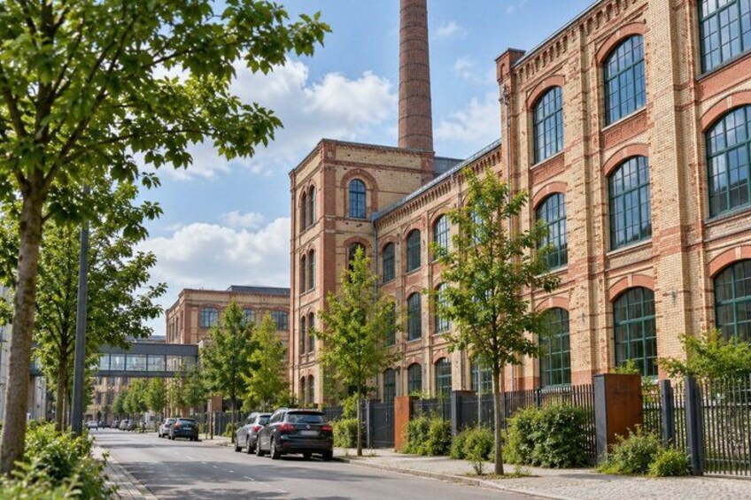 A brick building with large windows and a tall chimney. 5