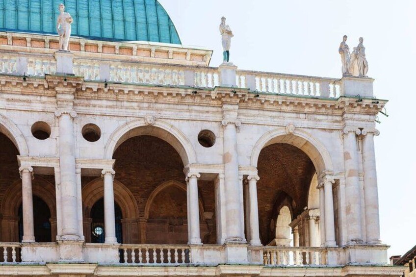 A classical building with arches, columns, and statues. 2