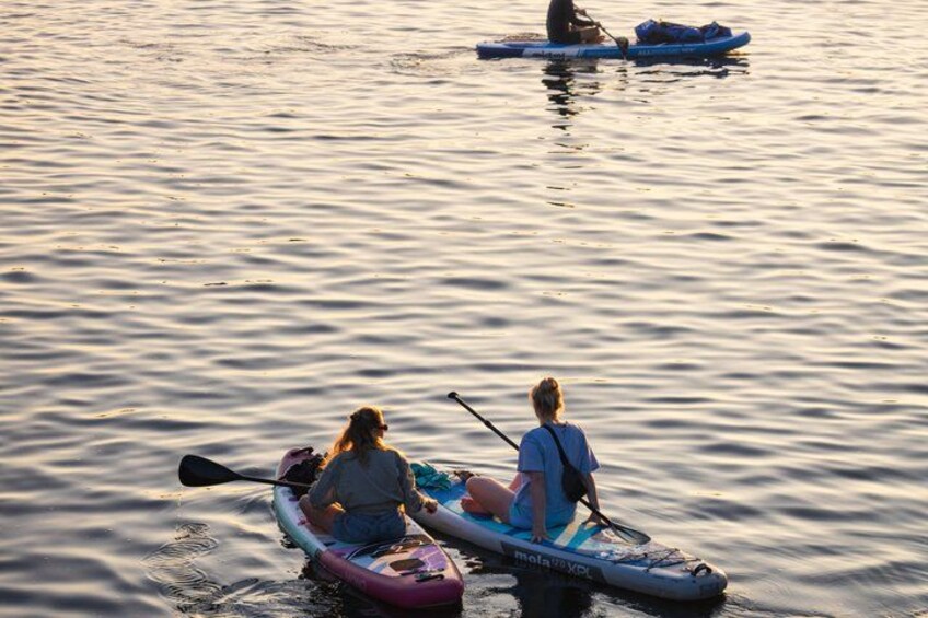 Two people kayaking on a calm body of water during sunset. 2