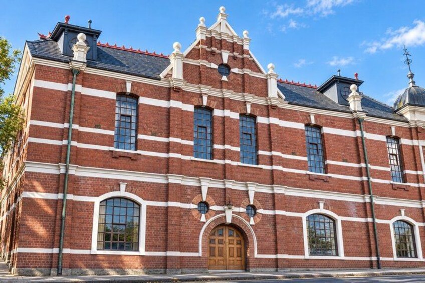 A red brick building with white trim, a central arched doorway, and a clock tower. 2