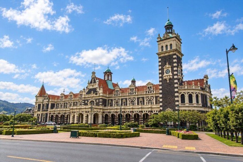A historic building with a clock tower, arched windows, and a red-tiled roof. 3