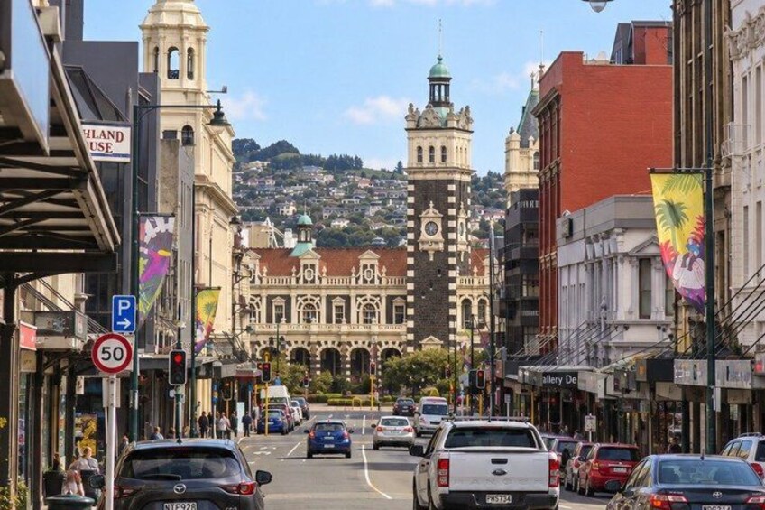A street with cars, a clock tower, and buildings. 5