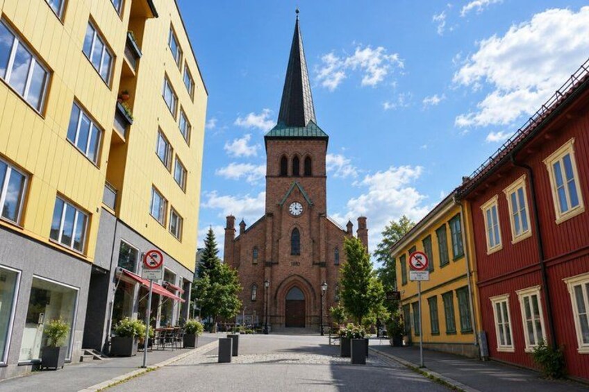 A church with a tall spire, a yellow building, and a red building. 4