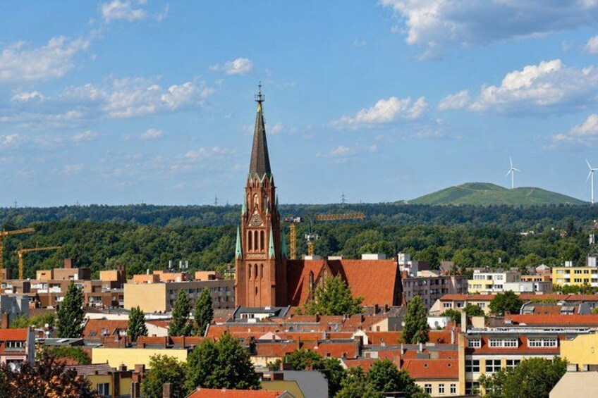 A town with a prominent church tower, wind turbines, and a hilly landscape in the background. 2