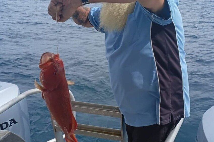 A person holding a large red fish on a boat. 5