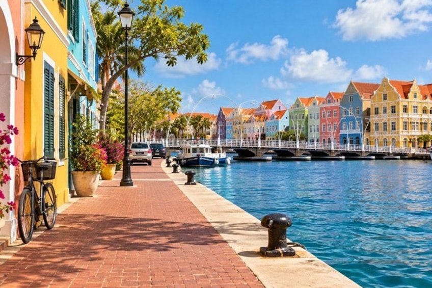 A canal with colorful buildings, a brick walkway, and boats. 4